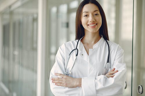 A woman in a white lab coat stands confidently for digital medical marketing.