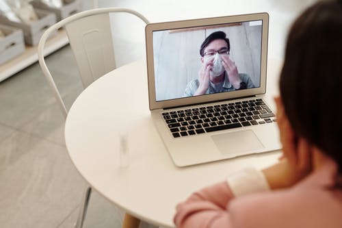 A woman engaged in a video chat on her laptop, showcasing online podiatry services with enthusiasm.